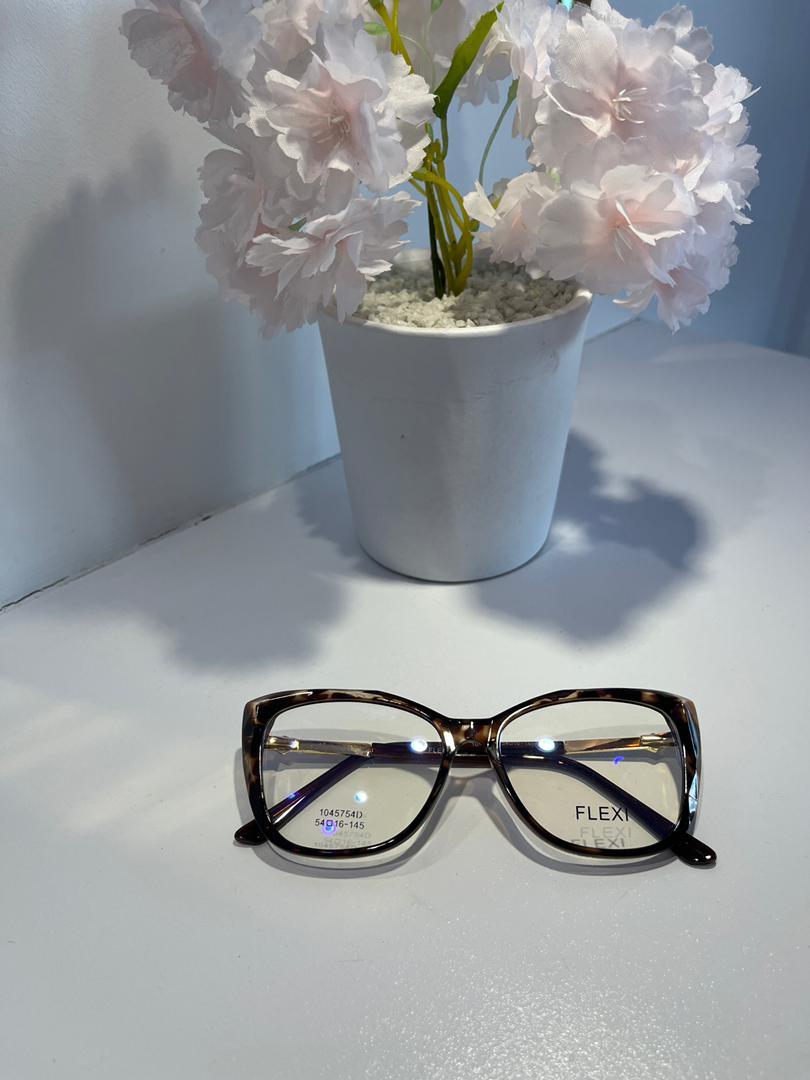 Pair of glasses on a white surface with a potted plant in the background