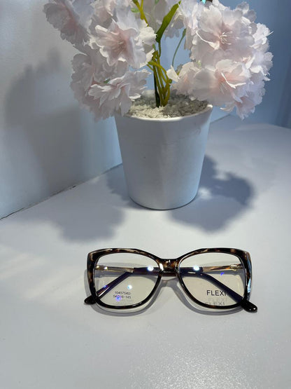 Pair of glasses on a white surface with a potted plant in the background